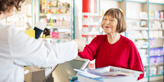 Older woman with short hair and a red top getting medication from Senderra Specialty Pharmacy
